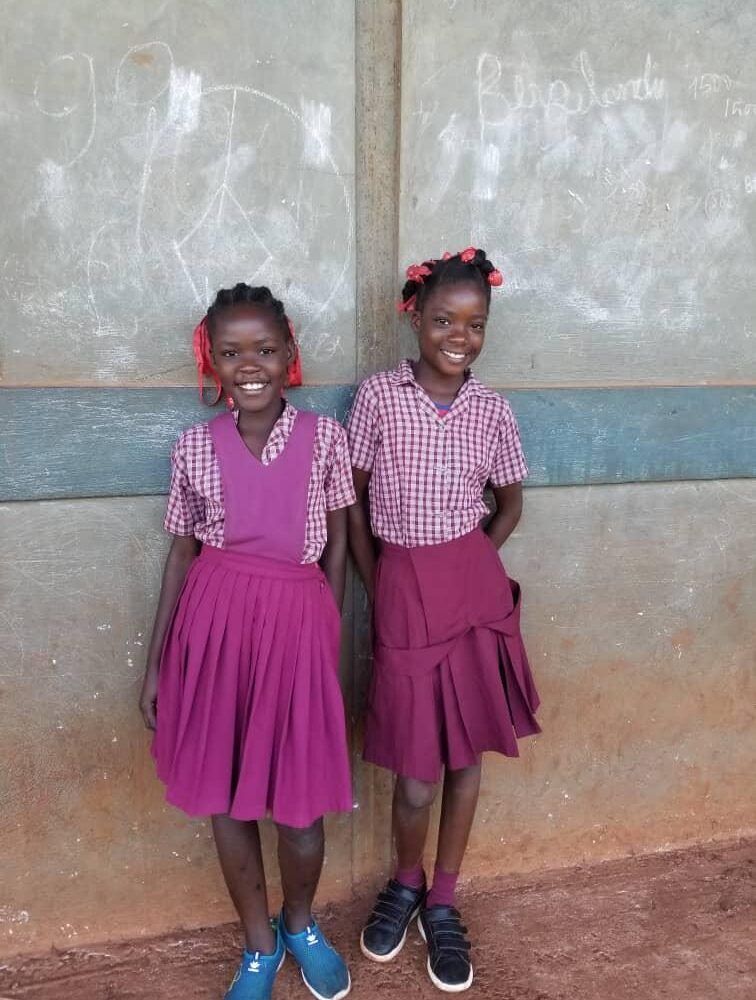 Two girls in school uniforms are standing next to each other