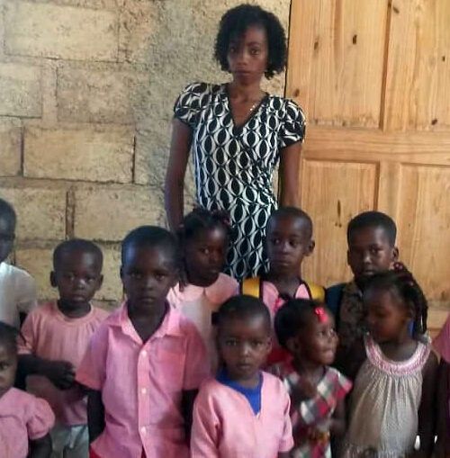 A woman stands in front of a group of children in pink shirts