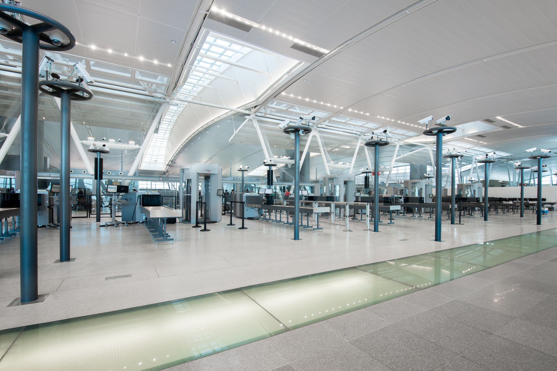 Airport security checkpoint with scanners and lines, bright, modern, and spacious.