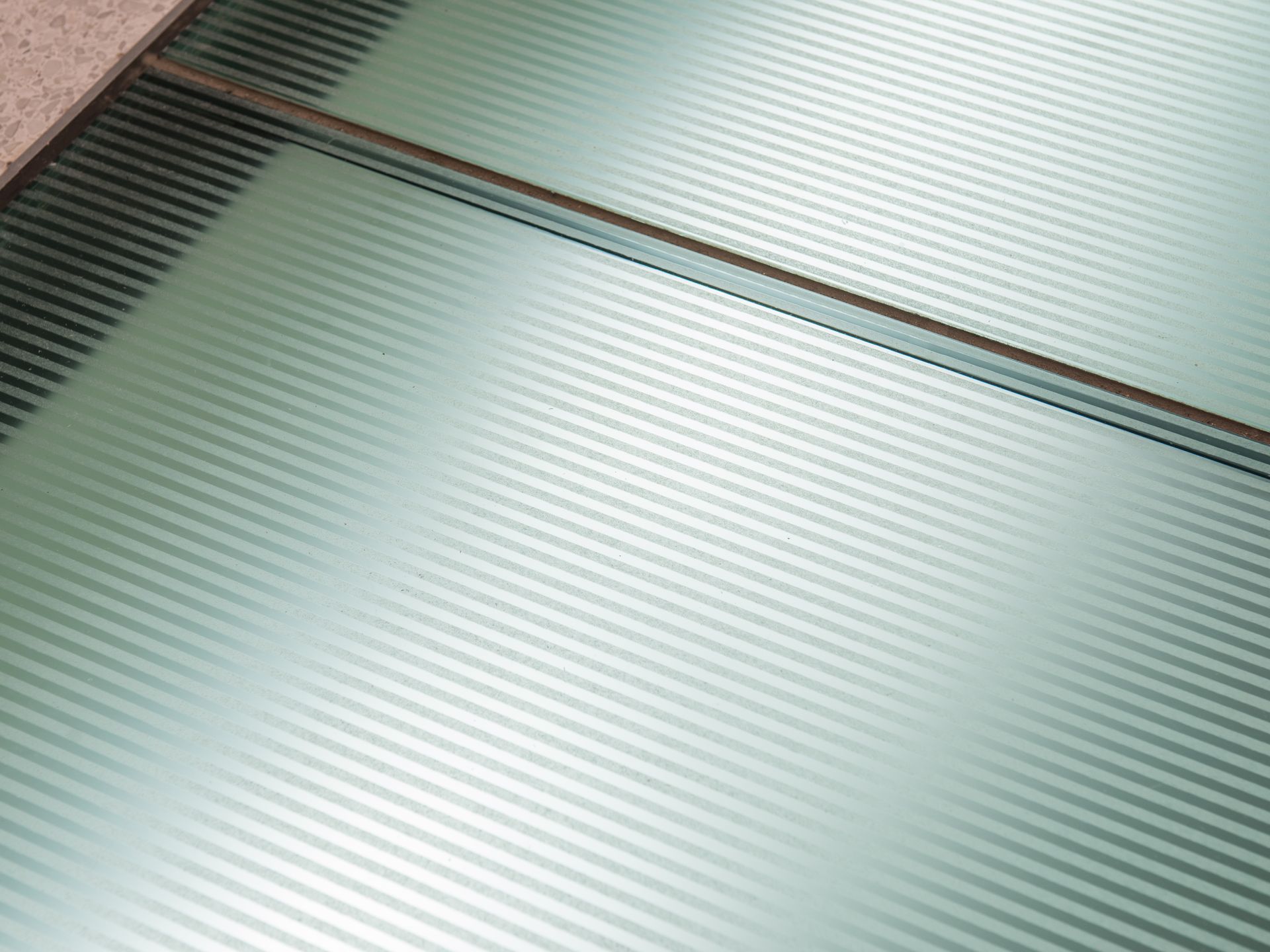 Frosted glass panels with diagonal stripes, part of a floor.