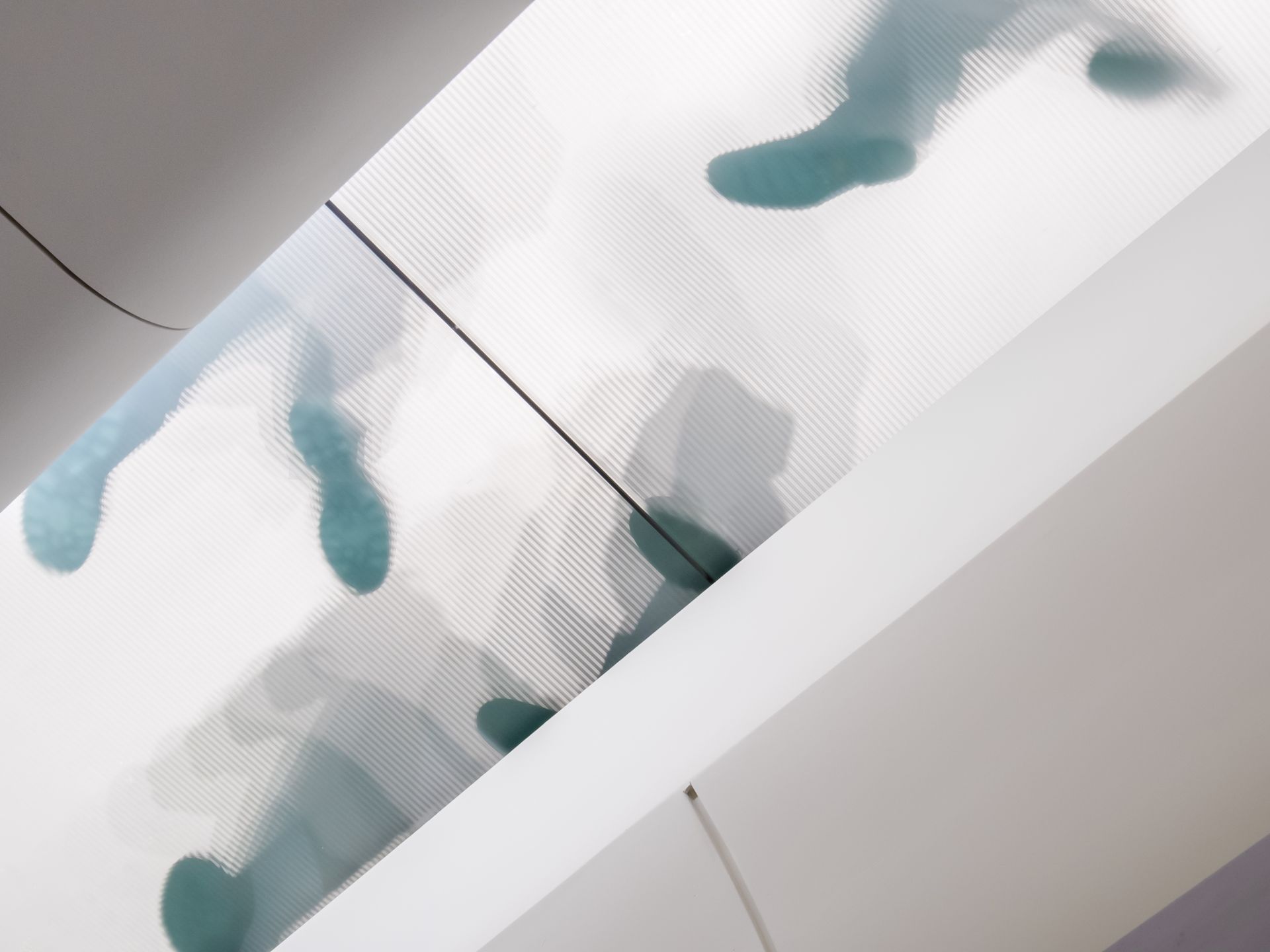 People's feet, rendered in aqua, walking across a translucent floor. The setting is a modern building.