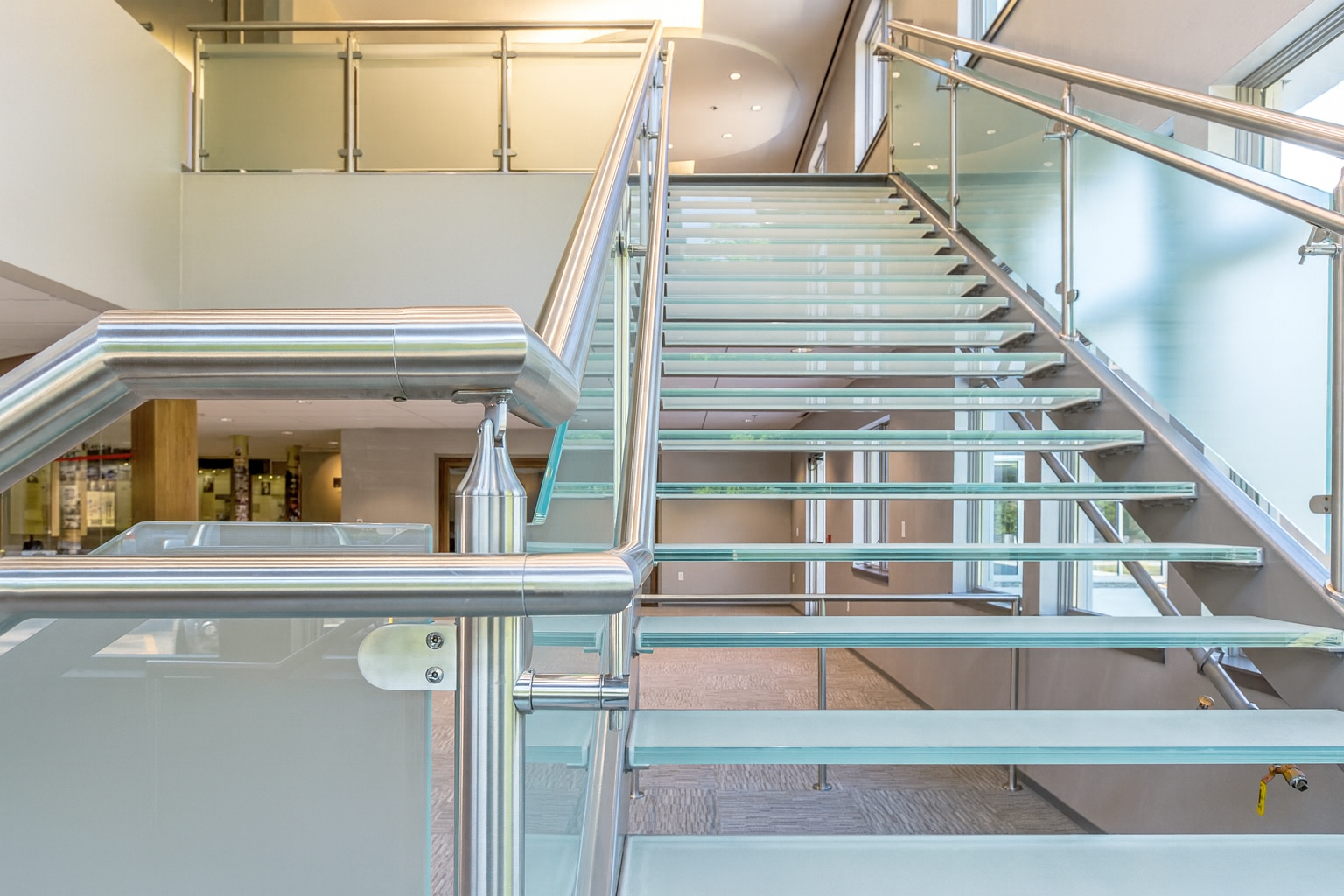 Glass staircase with metal railings in a modern building.