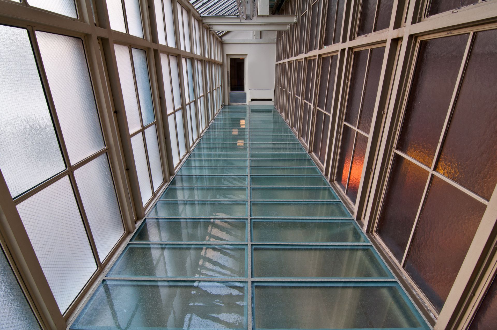 Glass floor walkway between rows of glass windows, natural light.