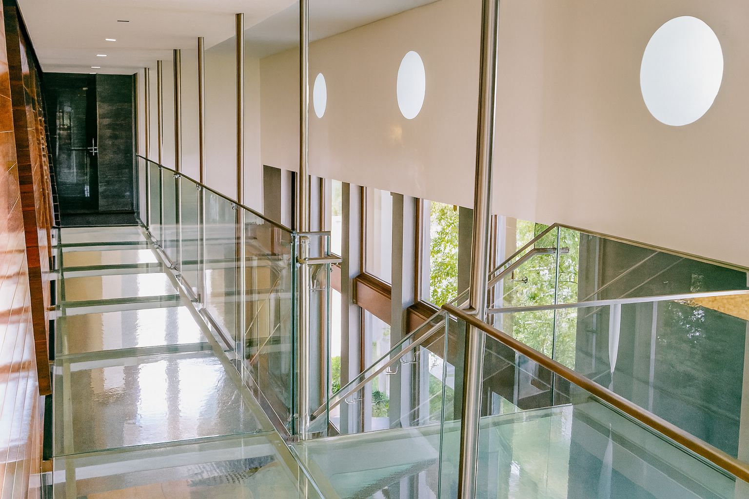 Glass and steel staircase with glass floor and wall, modern building.