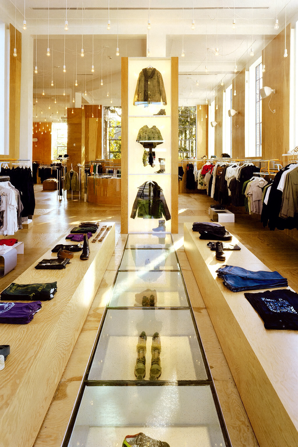 Clothing store interior with wooden display cases, glass walkway, and clothing racks.