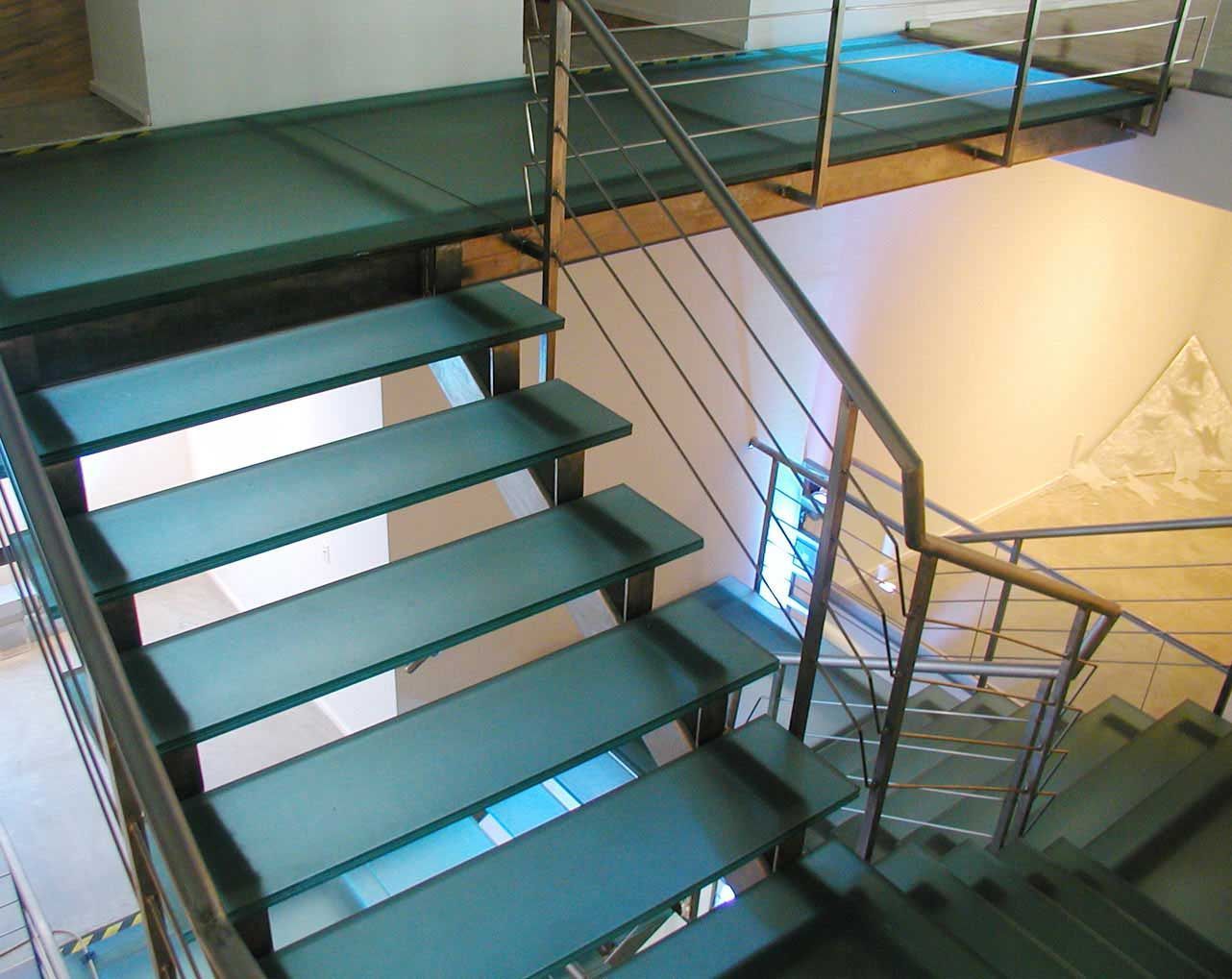 Modern staircase with teal glass steps and metal railing.