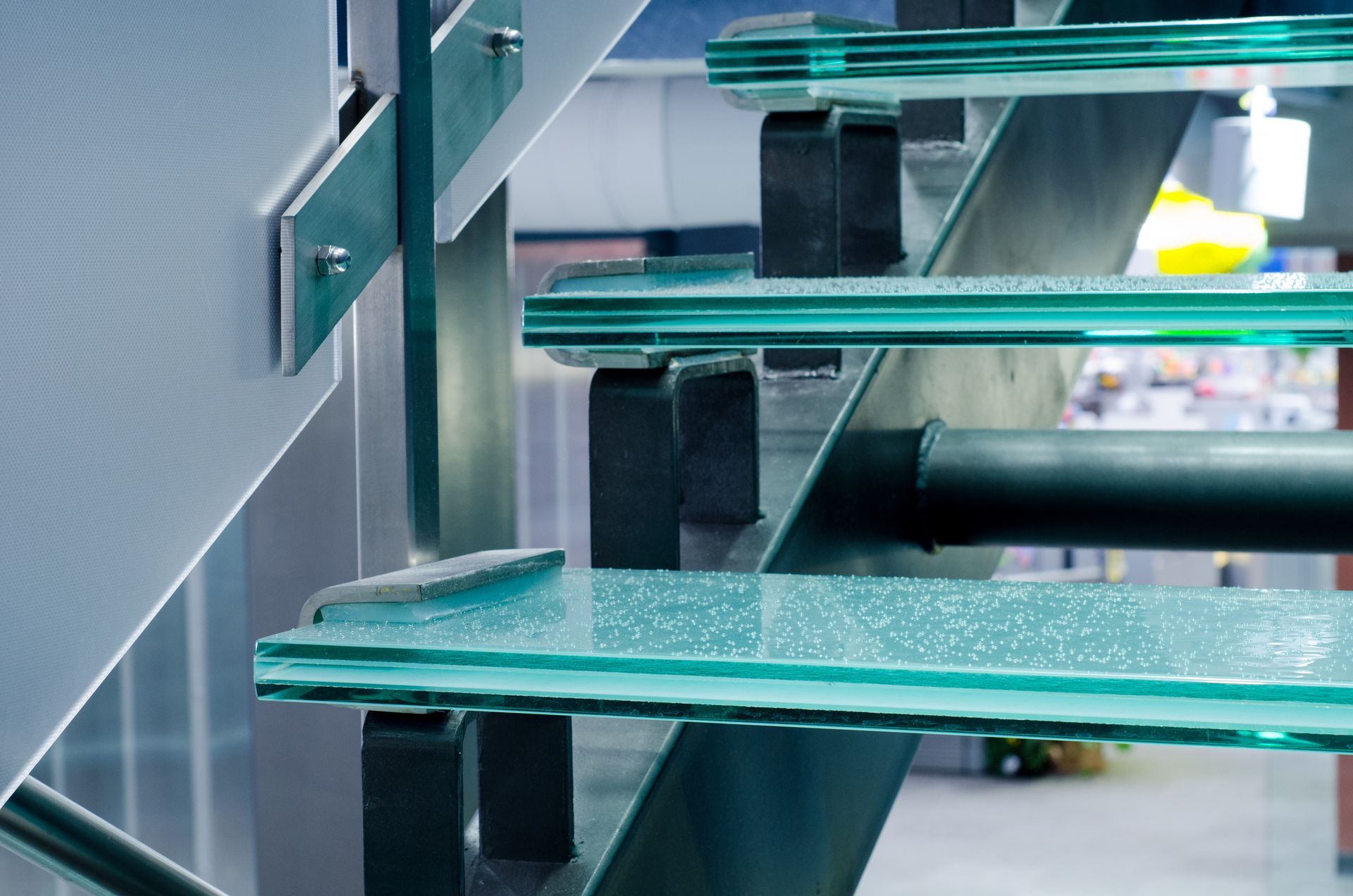 Glass stair treads with metal supports, bolted to a wall. Modern interior.