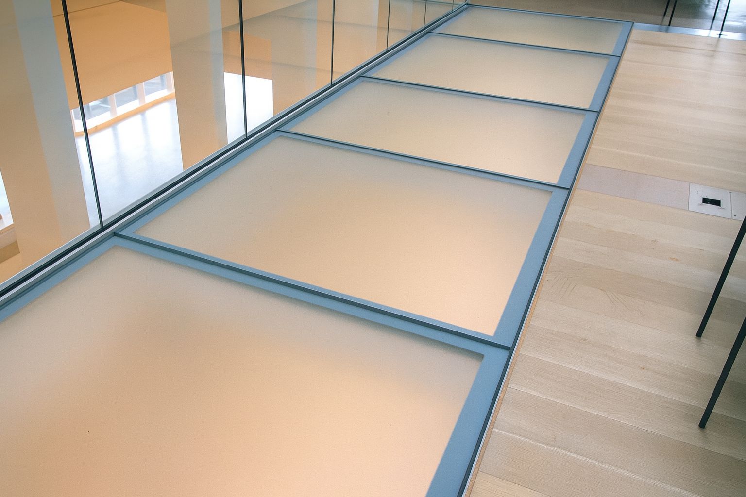 Glass floor panels in a modern building with wooden floors.