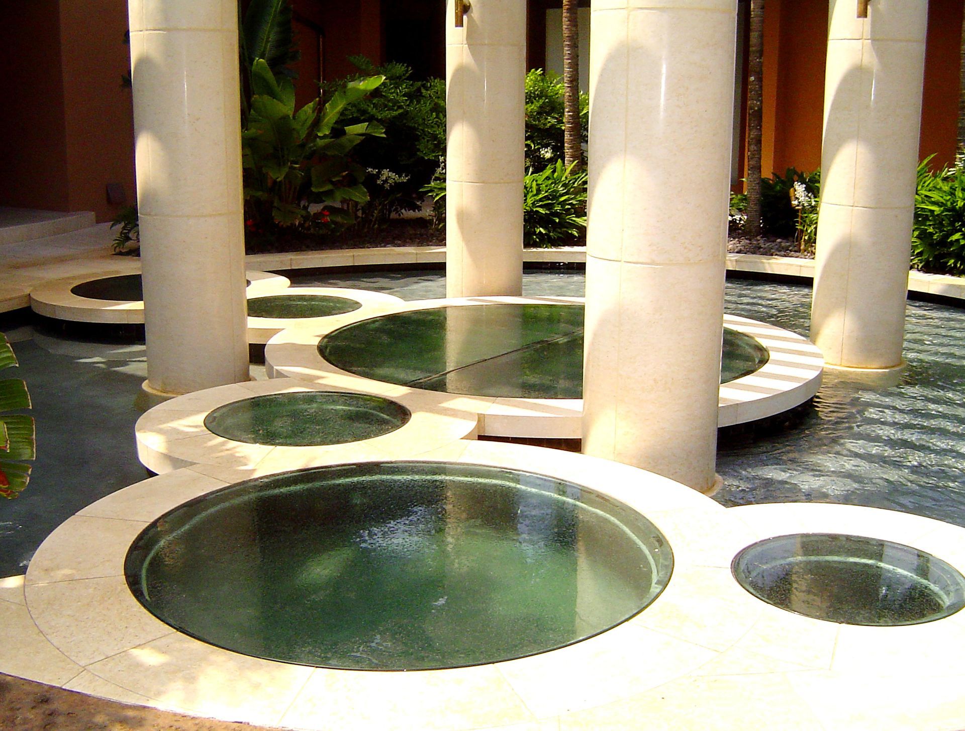 Round pool with clear water, surrounded by circular platforms and tall white pillars.