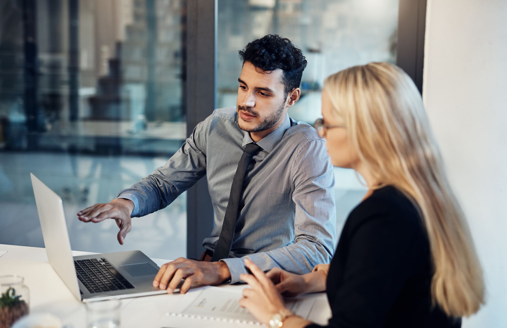 Two colleagues reviewing a laptop at a desk in a modern office Two colleagues reviewing a laptop at a desk in a modern office