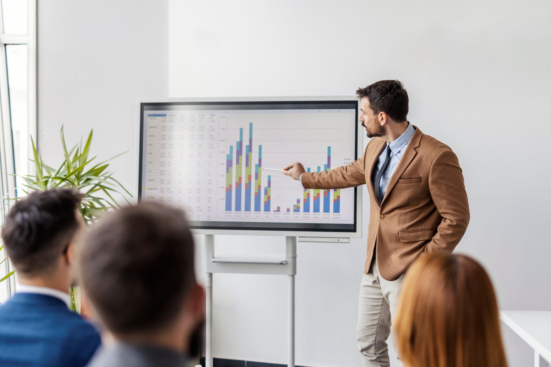 Business presenter pointing at a colorful chart on a screen during a meeting Business presenter pointing at a colorful chart on a screen during a meeting
