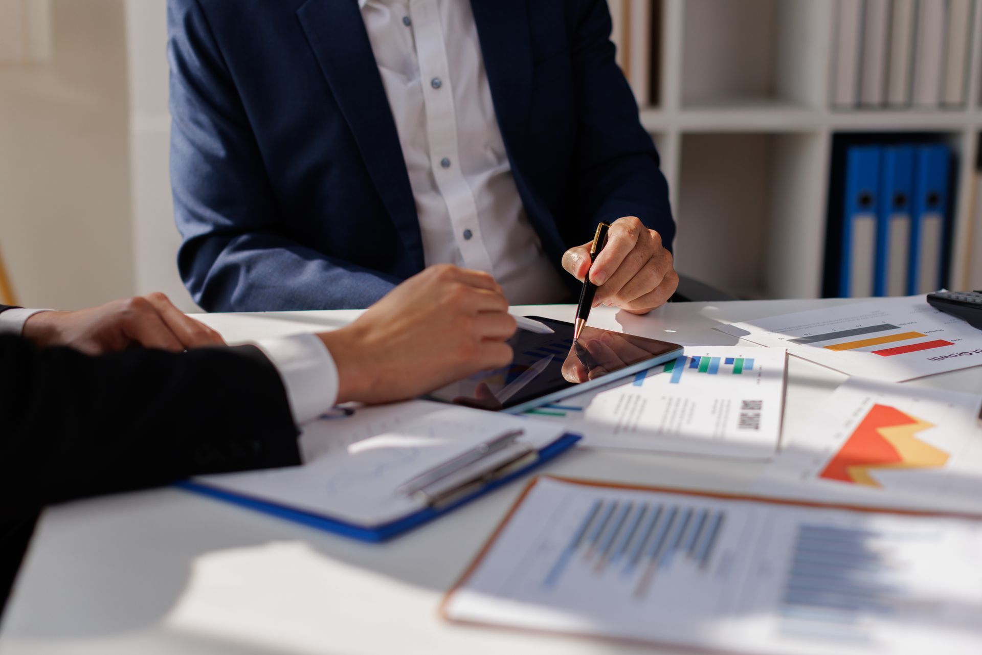 Business meeting with two people reviewing charts and documents at a desk Business meeting with two people reviewing charts and documents at a desk
