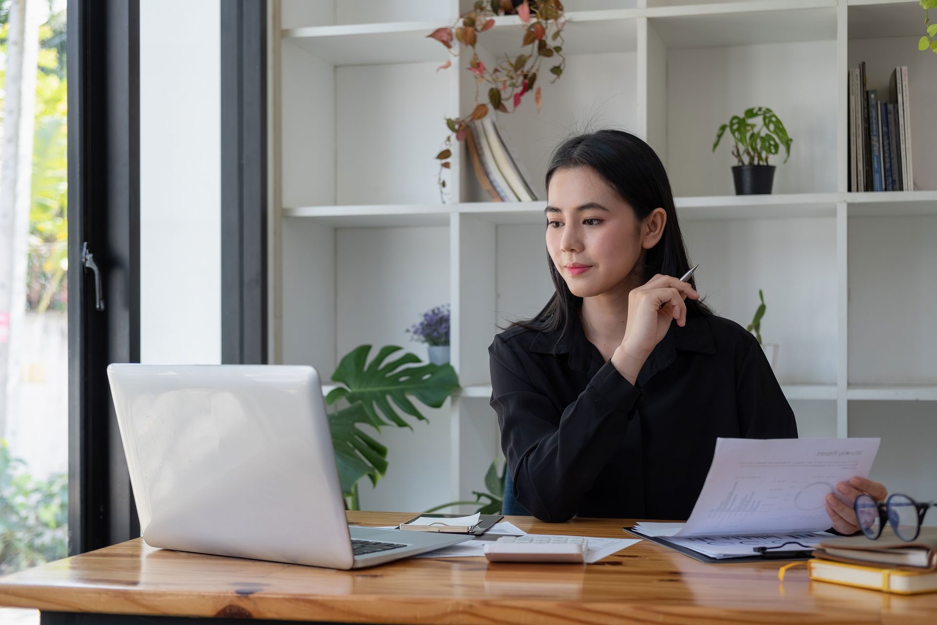 Woman working at a desk with a laptop and papers in a bright home office Woman working at a desk with a laptop and papers in a bright home office