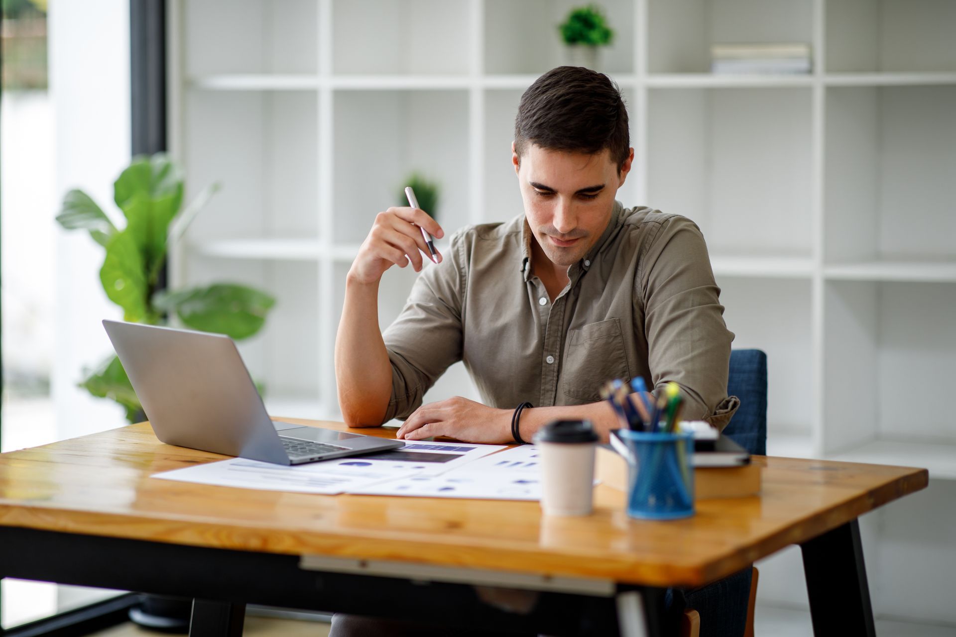Person working at a desk with a laptop and papers in a bright office Person working at a desk with a laptop and papers in a bright office