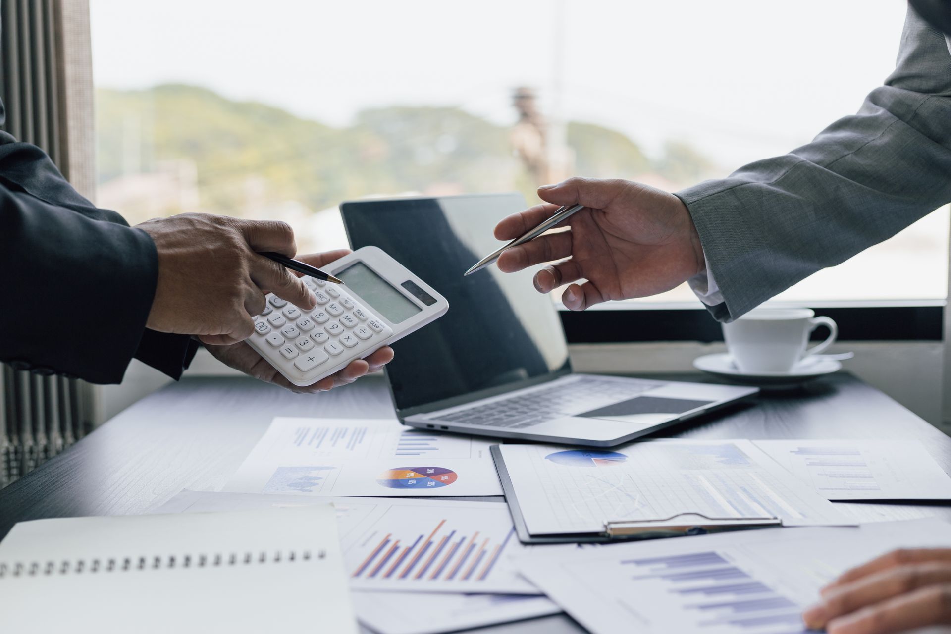 People in business attire discussing finances at a desk with a laptop, calculator, and documents. People in business attire discussing finances at a desk with a laptop, calculator, and documents.