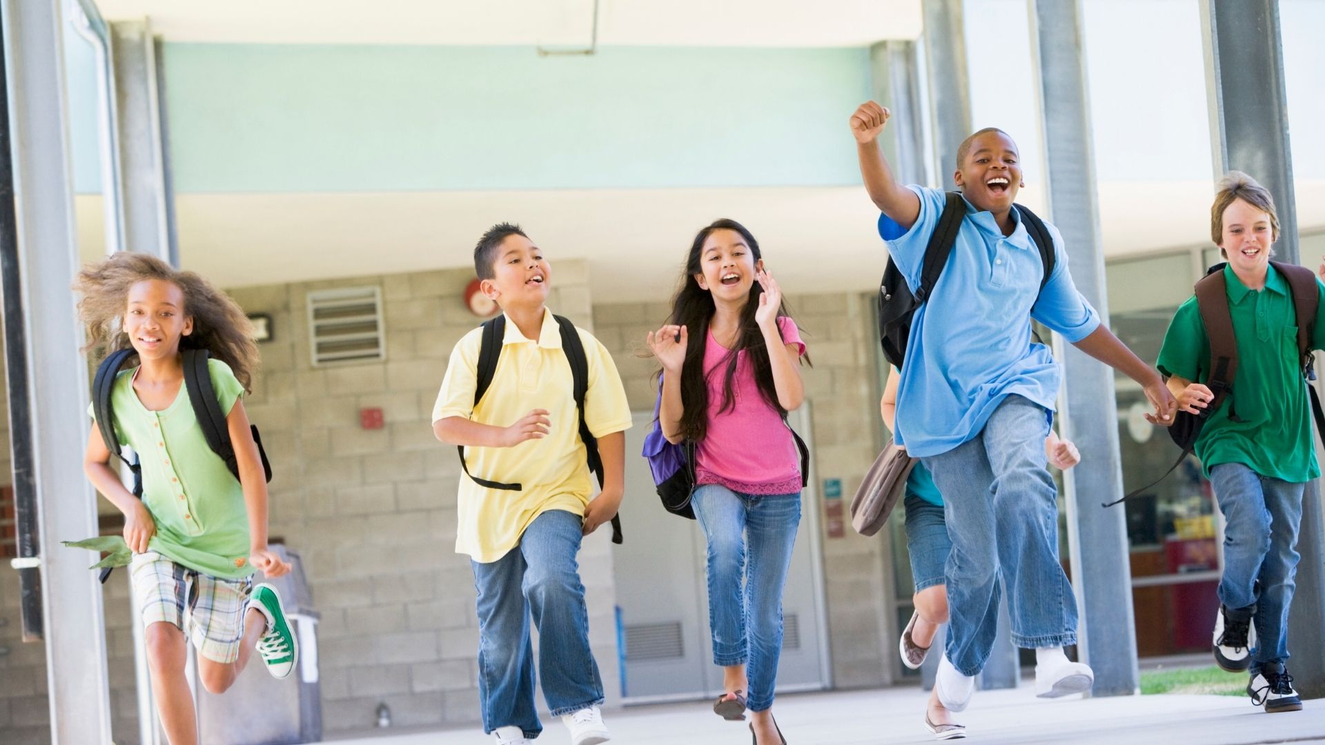 A group of children are running through a school hallway.