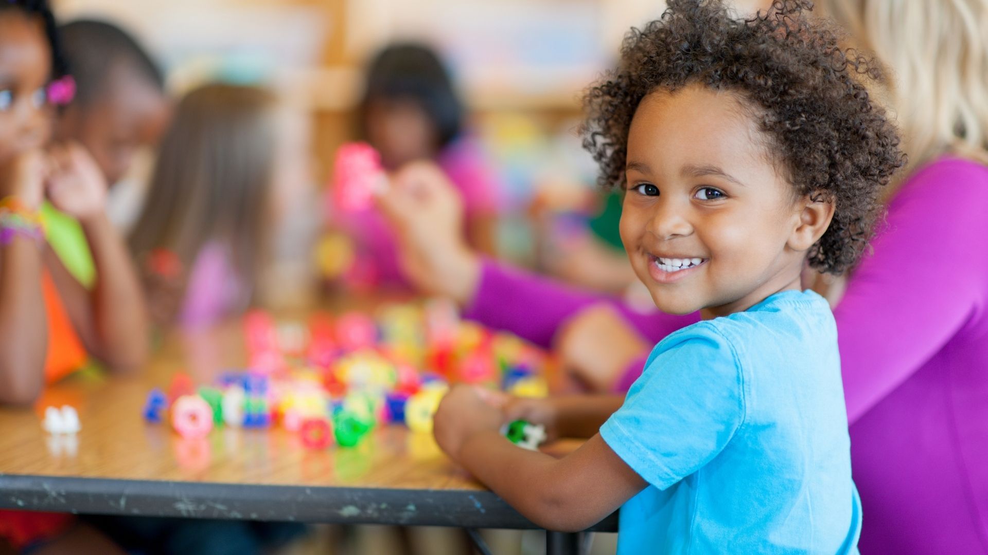 A young boy is sitting at a table playing with blocks.