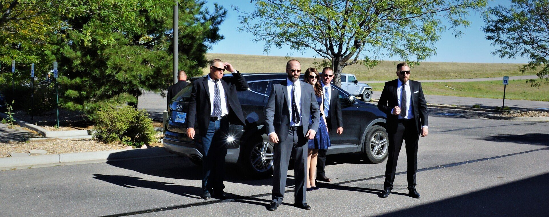 A group of people in suits and ties are standing in front of a car.