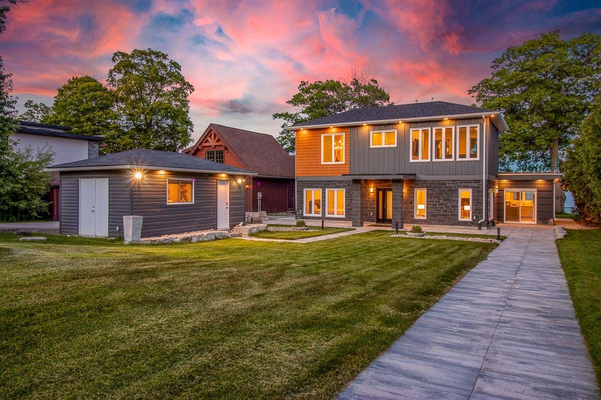 Modern two-story house with a garage and a brick walkway; dusk sky overhead.