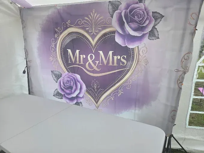Lavender “Mr & Mrs” heart backdrop with purple roses behind a white table