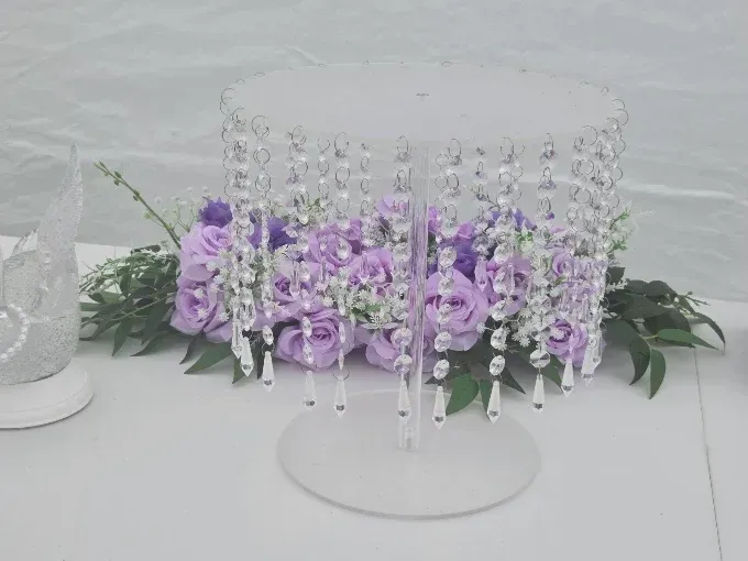 Crystal beaded candle holder with purple flowers and greenery on a white table