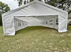 White outdoor event tent set up on a grassy lawn, viewed from the open front.