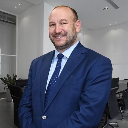 Smiling man in a blue suit standing in a modern conference room