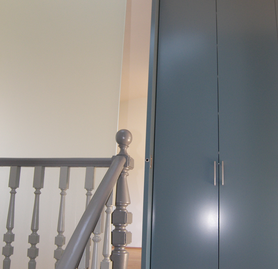 Eine Treppe mit einem grauen Geländer und einem blauen Schrank