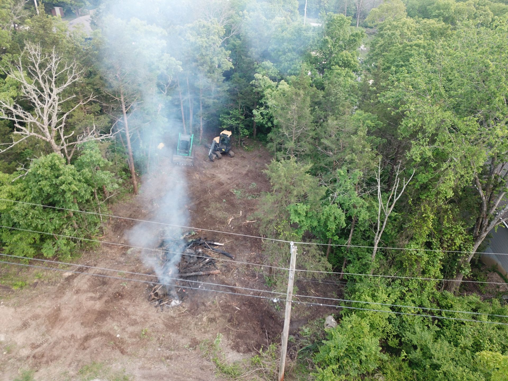 Smoke rising from a burned patch of forest, with a person on a motorbike near the center.
