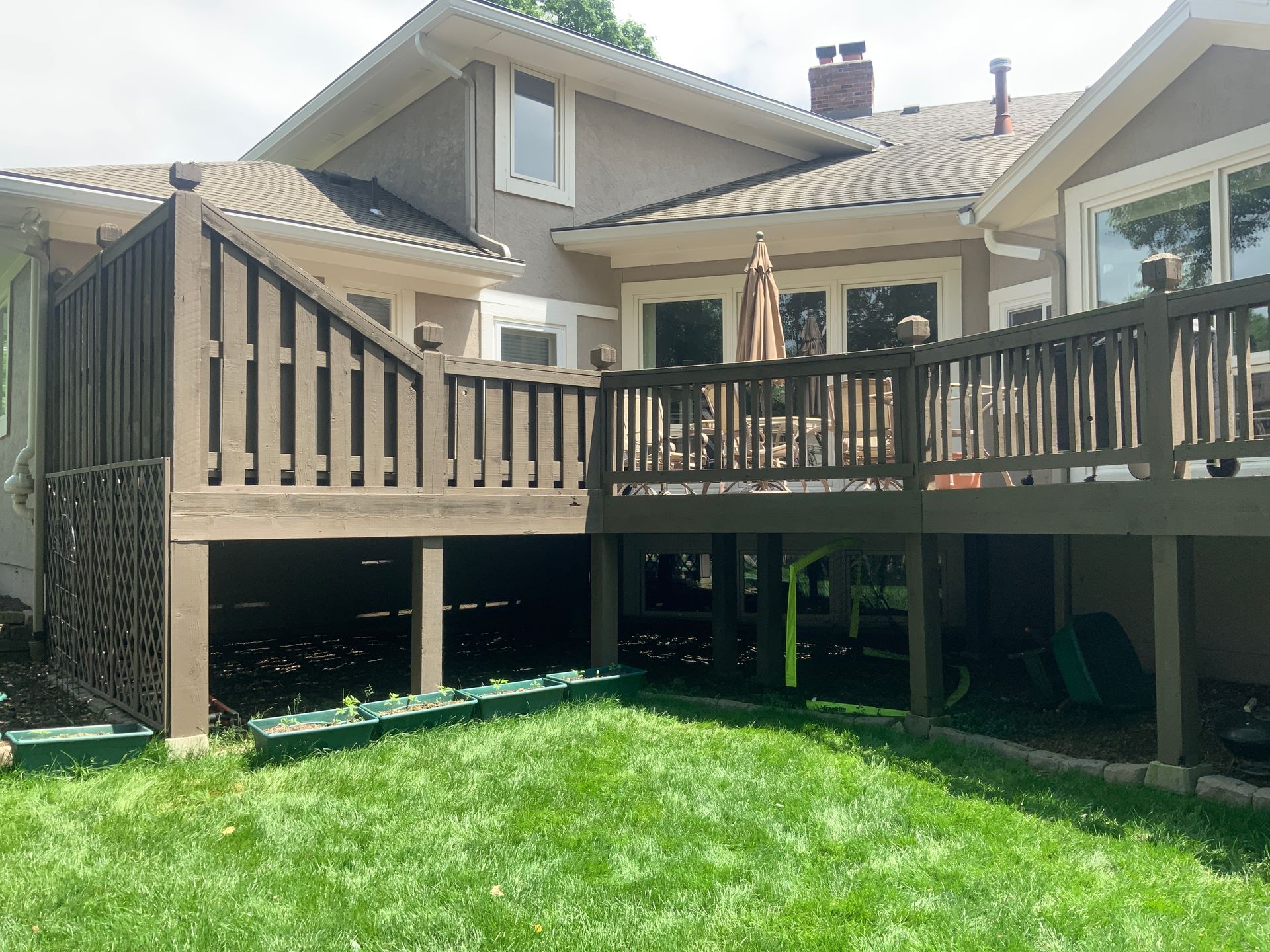 Wooden deck with lounge chairs under a covered patio, overlooking a wooded garden.