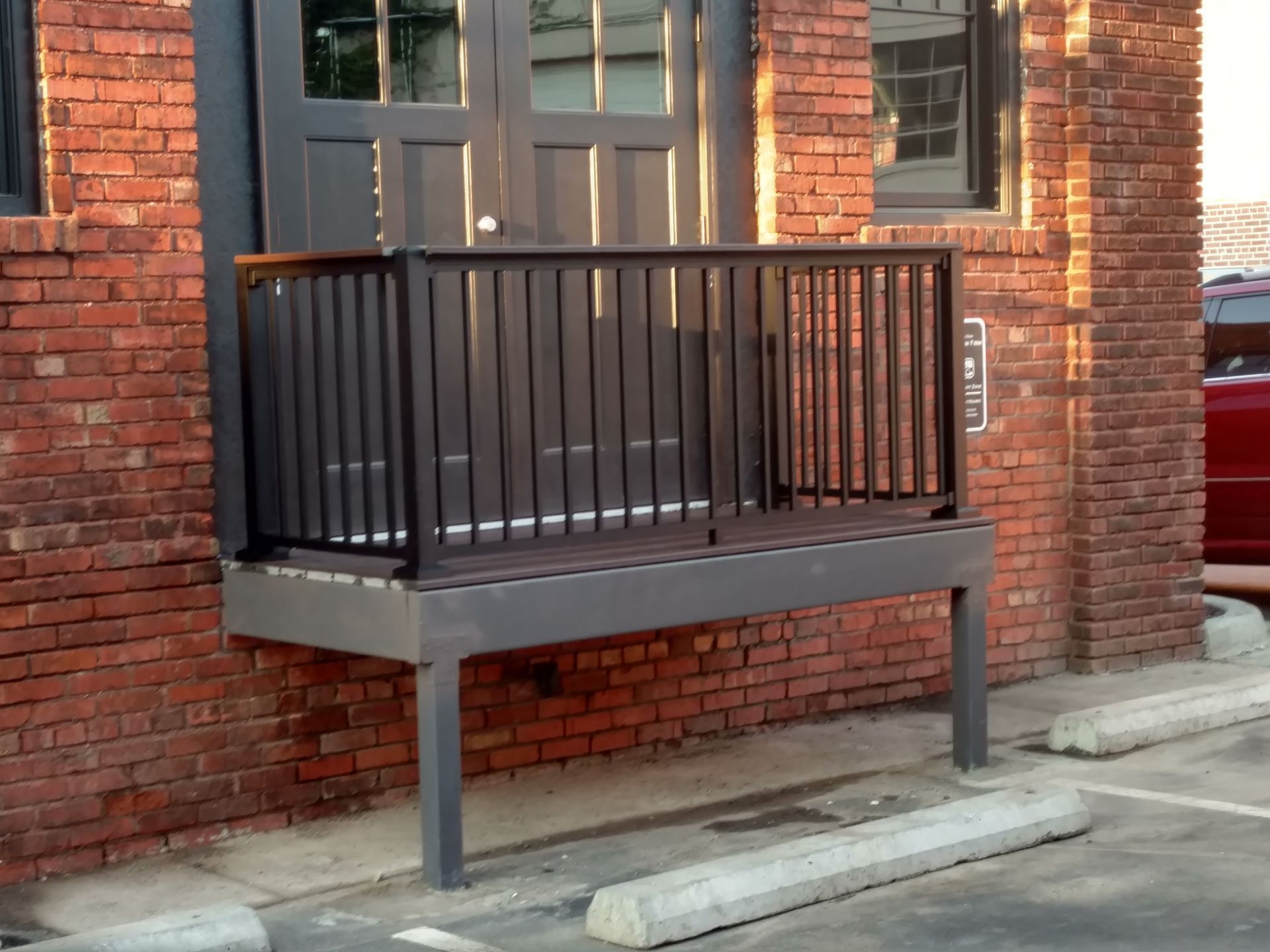 Black metal accessibility ramp beside a brick building entrance with a glass door