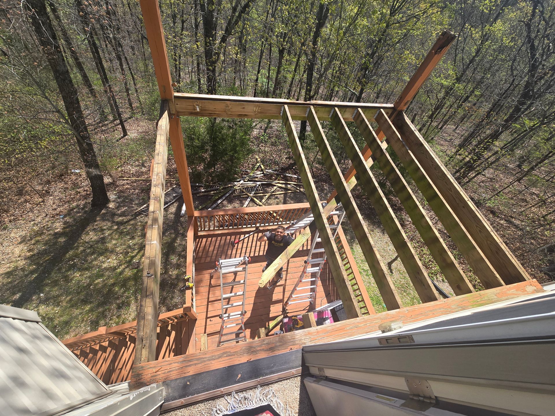 Wooden roof framing over a brick structure on a hillside, with forested trees below.