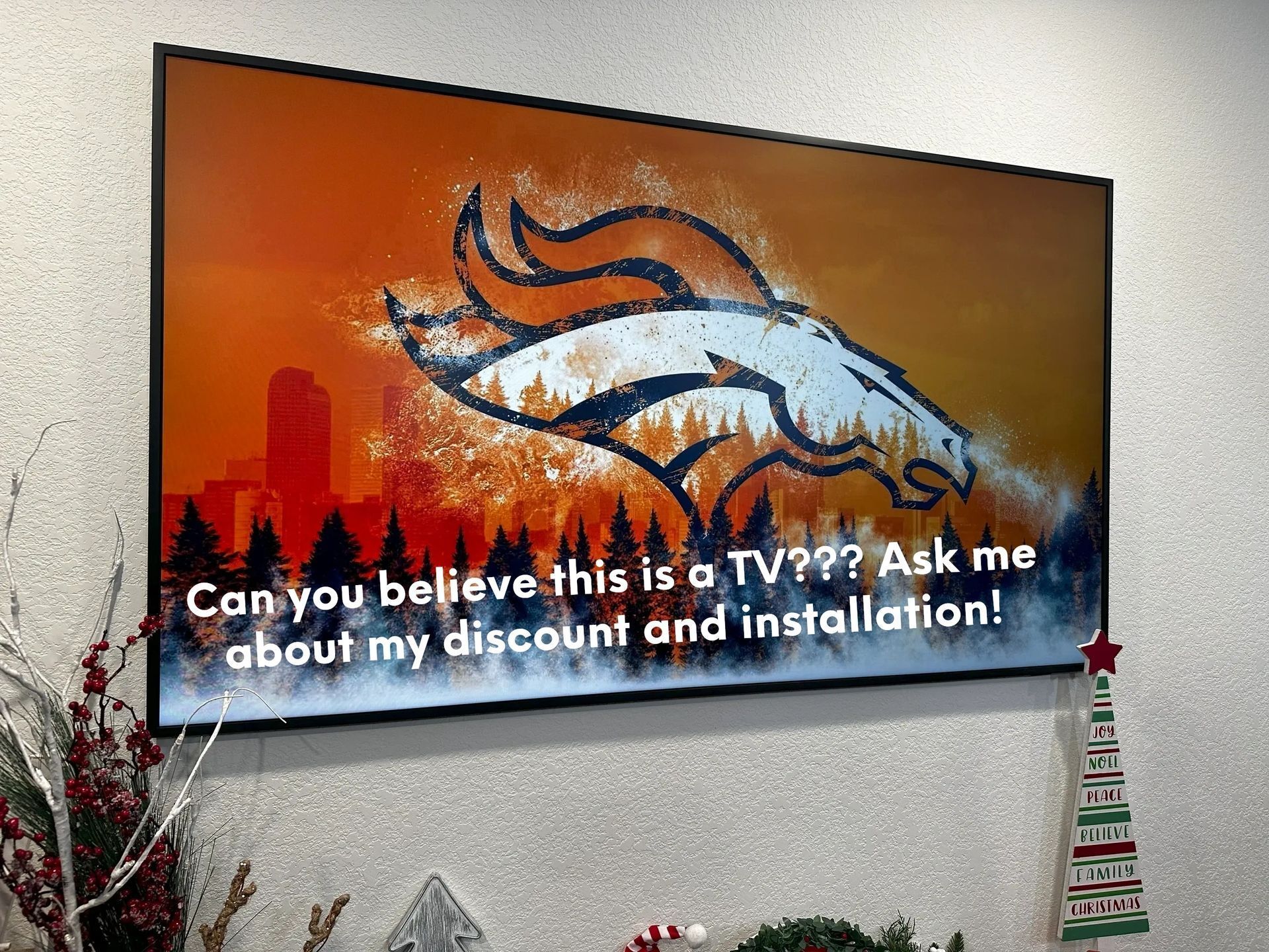 A painting of a broncos logo is hanging on a wall.