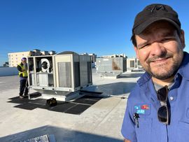 Technician inspecting wiring inside an HVAC unit with a flashlight