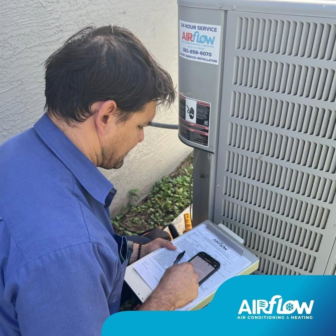 Technician in blue shirt checking an outdoor HVAC unit with a clipboard.