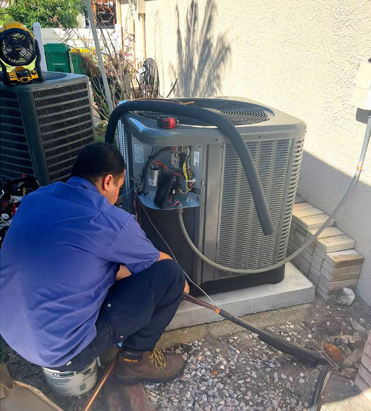 Technician inspecting an outdoor air conditioner unit with tools beside it