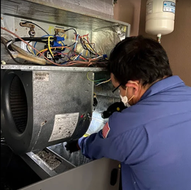 Technician inspecting wiring inside an HVAC unit with a flashlight