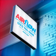 Illuminated Airflow sign projecting from a building against a blue and pink wall