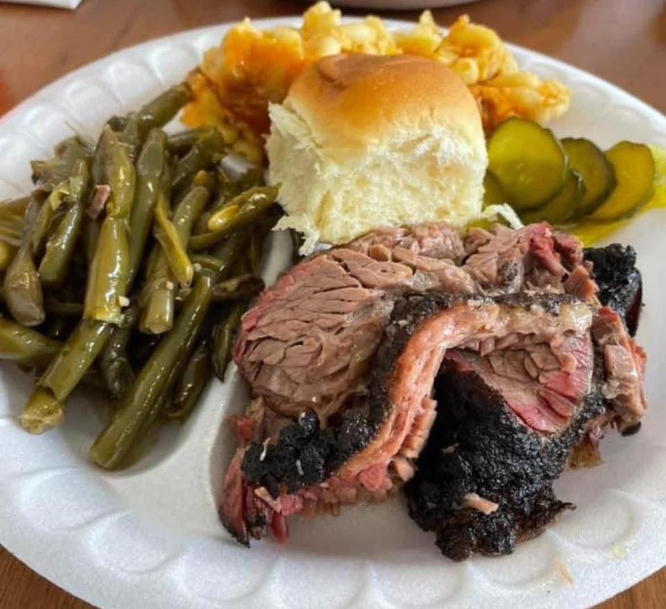 A white plate topped with meat green beans and pickles