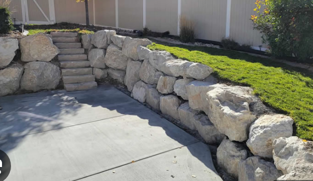 A stone wall with stairs leading up to it in a yard.