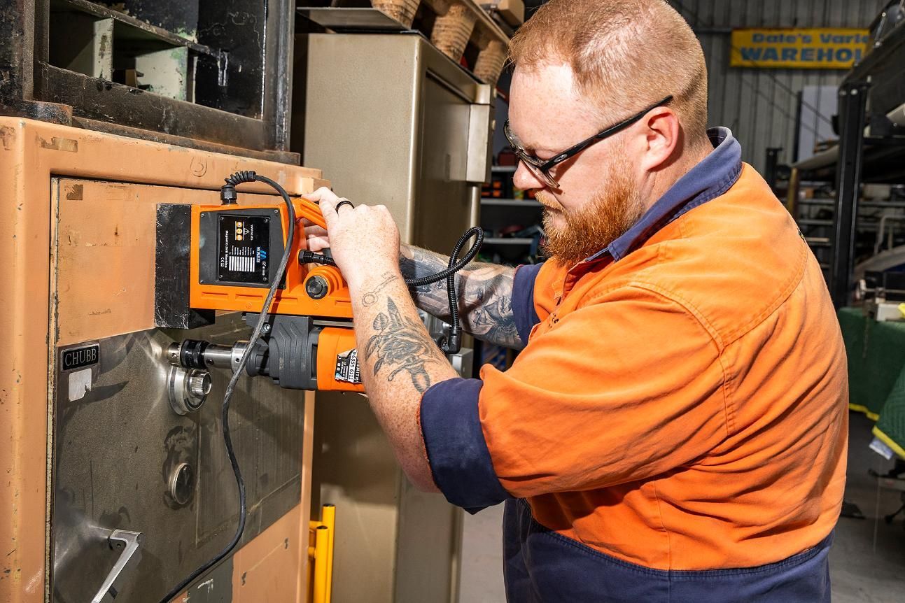 A Man Using Machinery to Open a Safe in a Workshop — Active 247 Locksmith and Security Services Forster In Forster, NSW