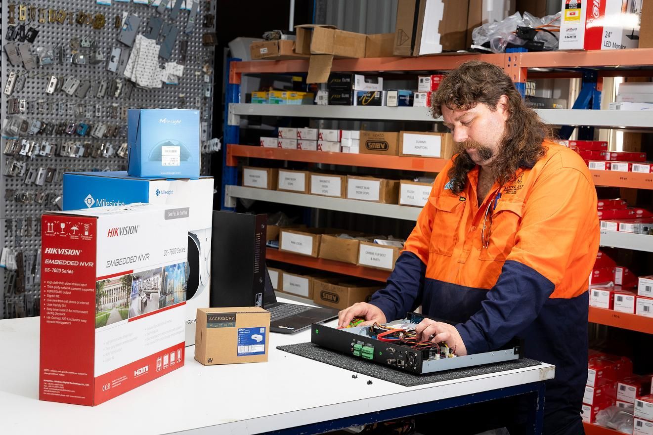 A Person With a Mullet Working on a Device at a Counter — Active 247 Locksmith and Security Services Forster In Forster, NSW