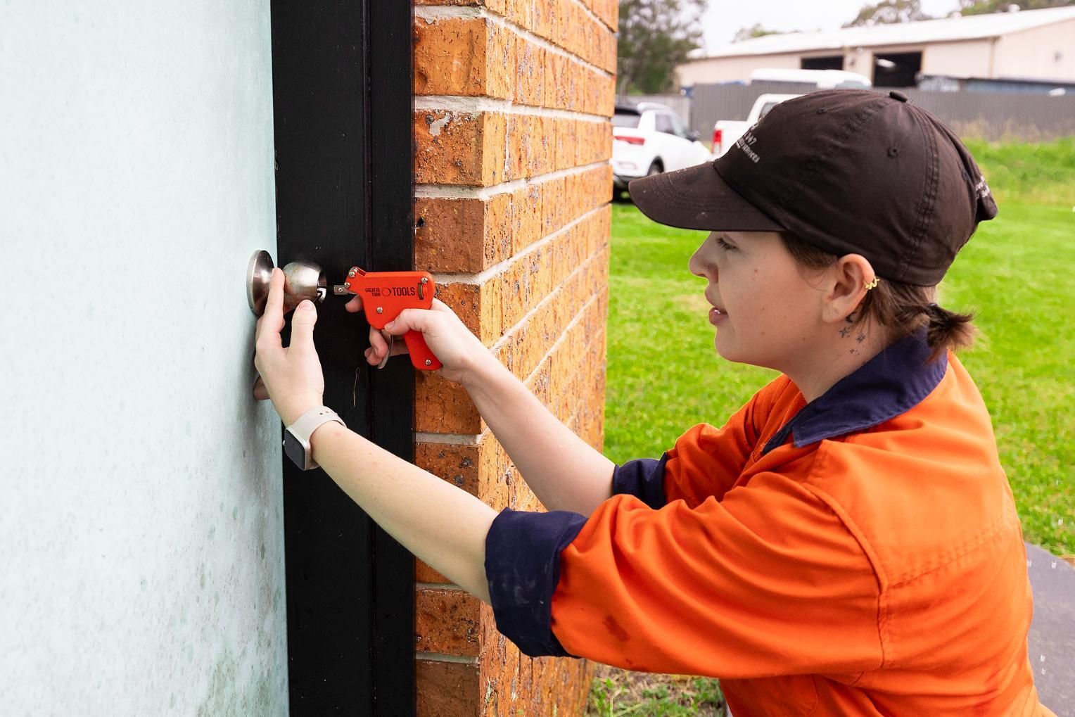 Woman in Orange Shirt Installing a Door Handle — Active 247 Locksmith and Security Services Forster In Forster, NSW