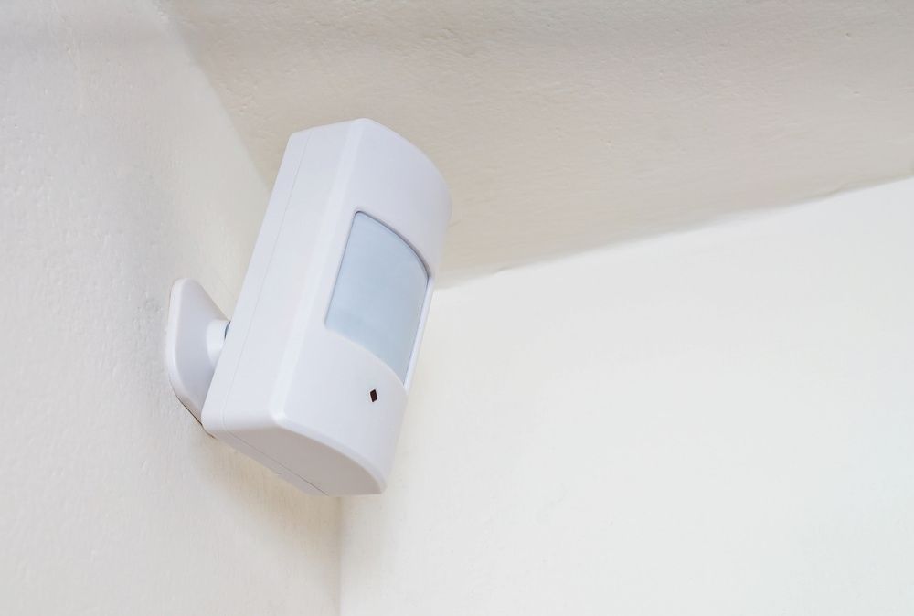 White Motion Sensor Mounted on a White Wall in a Corner — Active 247 Locksmith and Security Services Forster In Forster, NSW