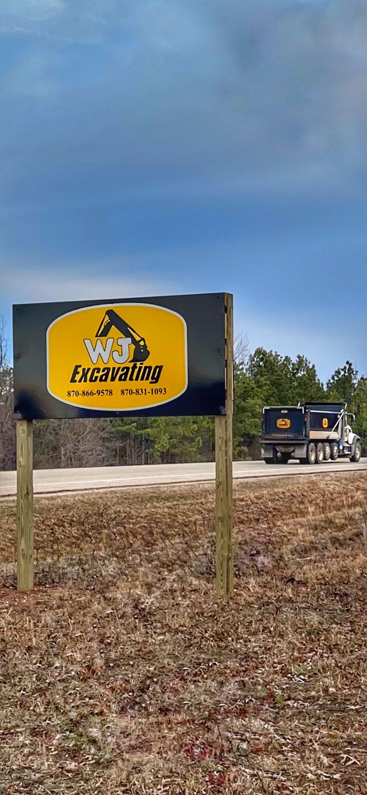 Yellow-and-black sign reading “Zion Church” in a field, with a truck in the background under a cloudy sky