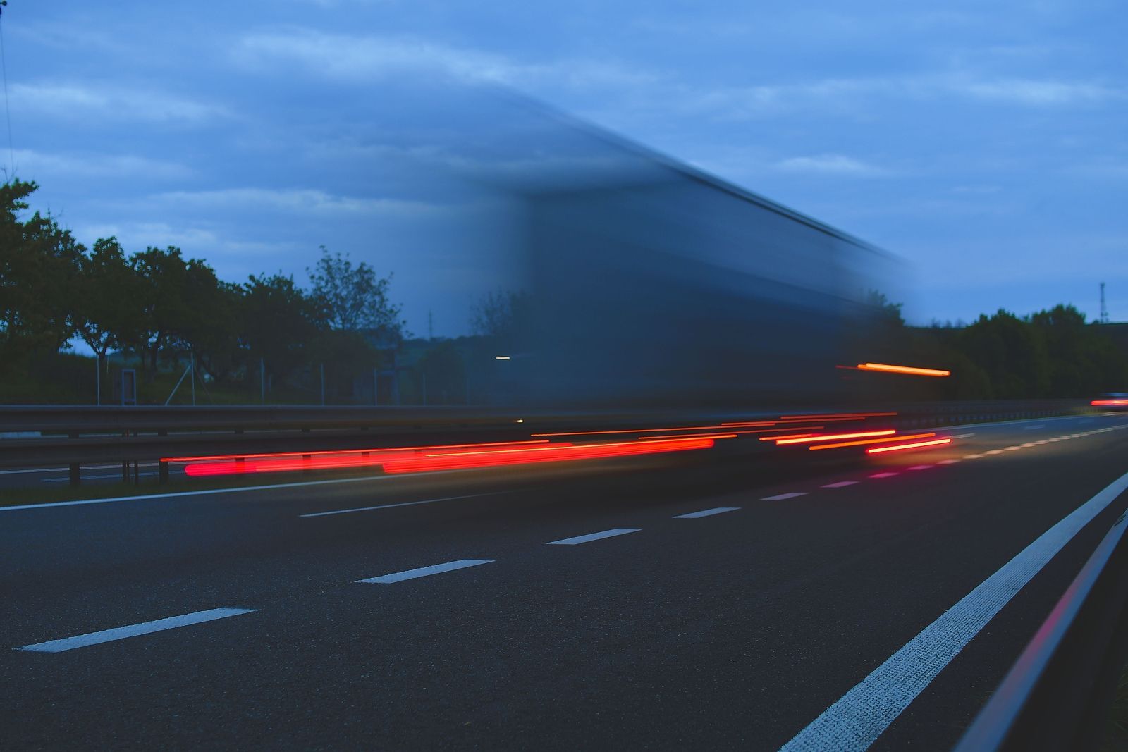 A truck is driving down a highway at night.