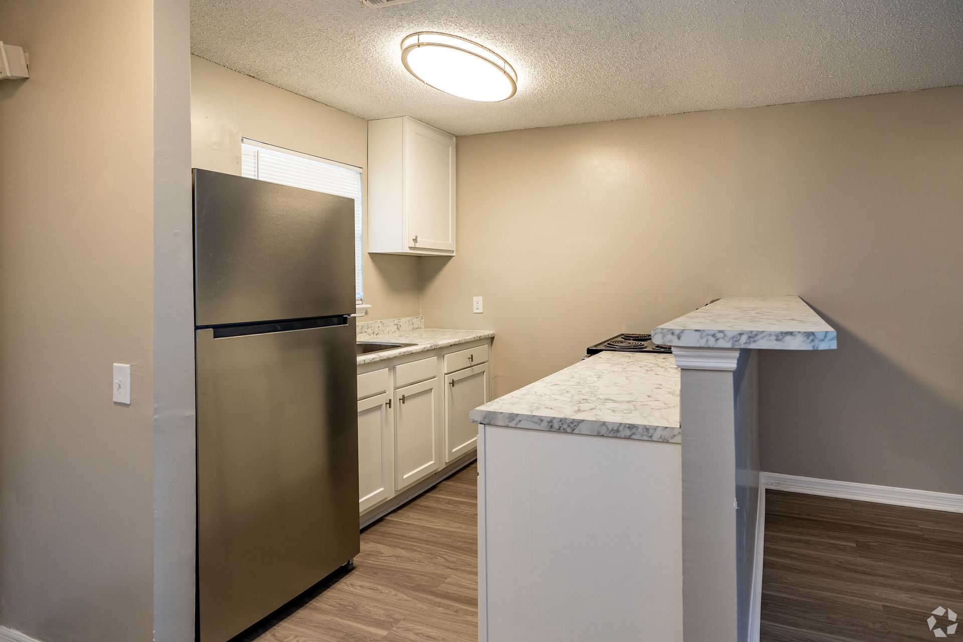 Modern kitchen with stainless steel refrigerator, white cabinets, and a breakfast bar at Caroline Village in Jacksonville, FL.
