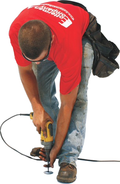 Construction worker using a drill. He's wearing a red shirt, blue jeans, and safety glasses.