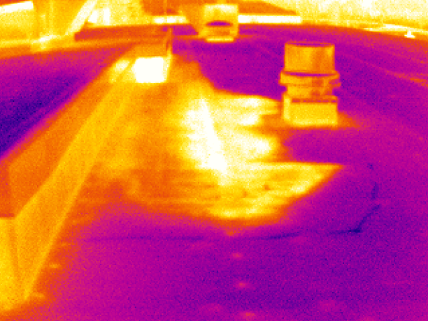 Thermal image of a roof showing warm areas in orange/yellow and cooler areas in purple/magenta, with equipment present.