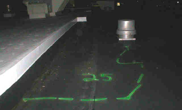 Dark rooftop with a vent and a green-painted outline, marked 